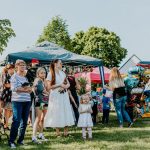 A lively outdoor gathering with families enjoying balloons and a sunny day.