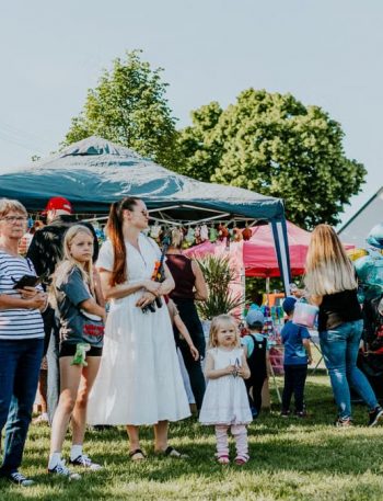 A lively outdoor gathering with families enjoying balloons and a sunny day.