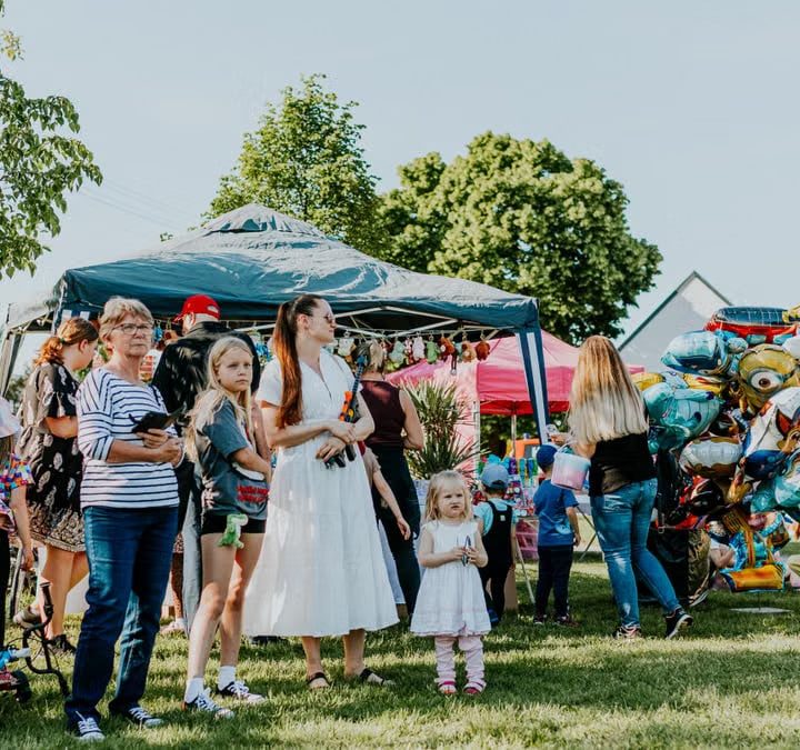 A lively outdoor gathering with families enjoying balloons and a sunny day.